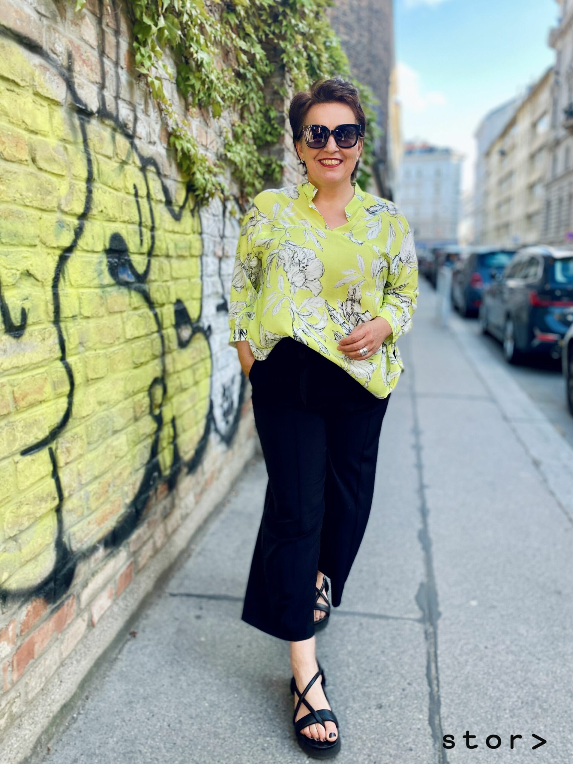 Schöne Mode in großen Größen von stor> Wien. Elegante Bluse in Gelbgrün mit weißen Blumenmuster und schwarzer Hose.